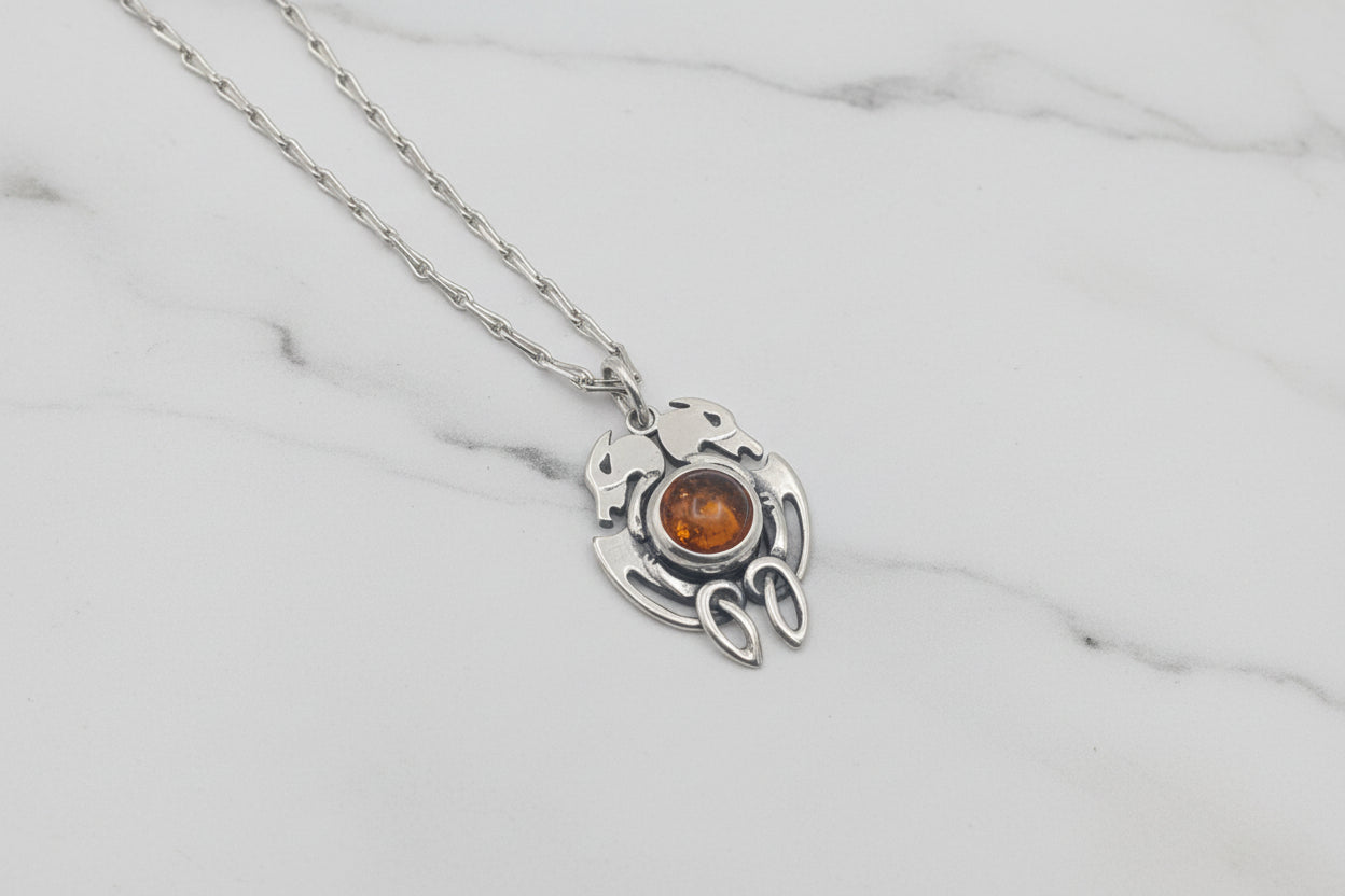 Silver necklace with a pendant featuring a brown gemstone on a light gray background