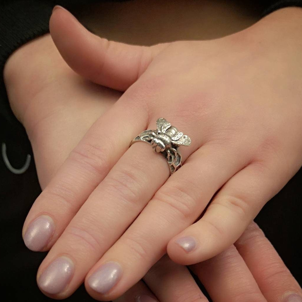 Silver butterfly ring on a person's finger with a blurred background