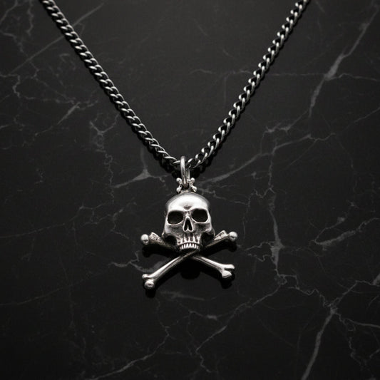 Sterling silver skull and crossbones pendant necklace with a heavy curb chain displayed on a black marble background.