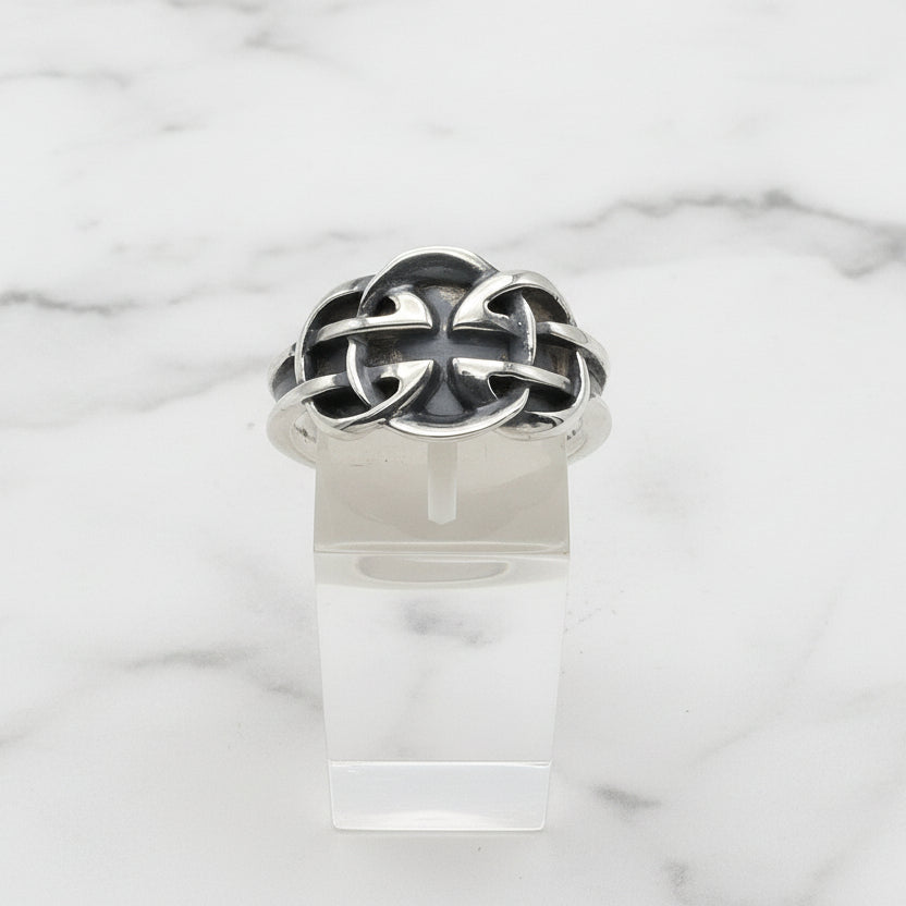 Silver Celtic ring with a unique design on a clear stand against a white background