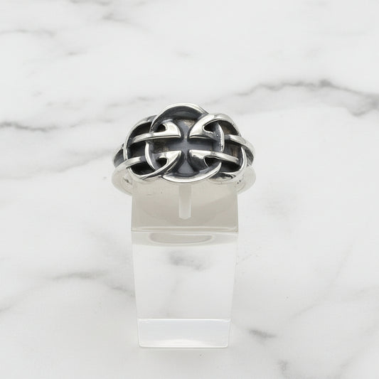 Silver Celtic ring with a unique design on a clear stand against a white background