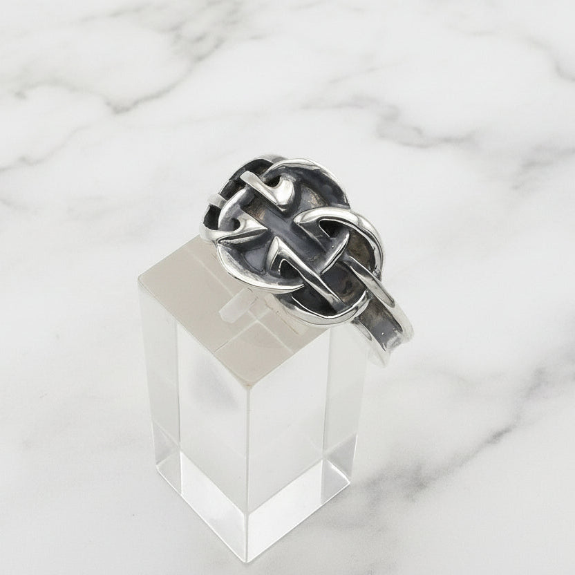 Silver ring with a unique design on a clear stand against a white background