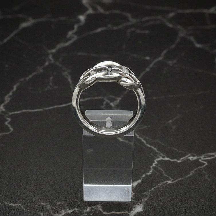 Silver ring on a clear stand against a black background