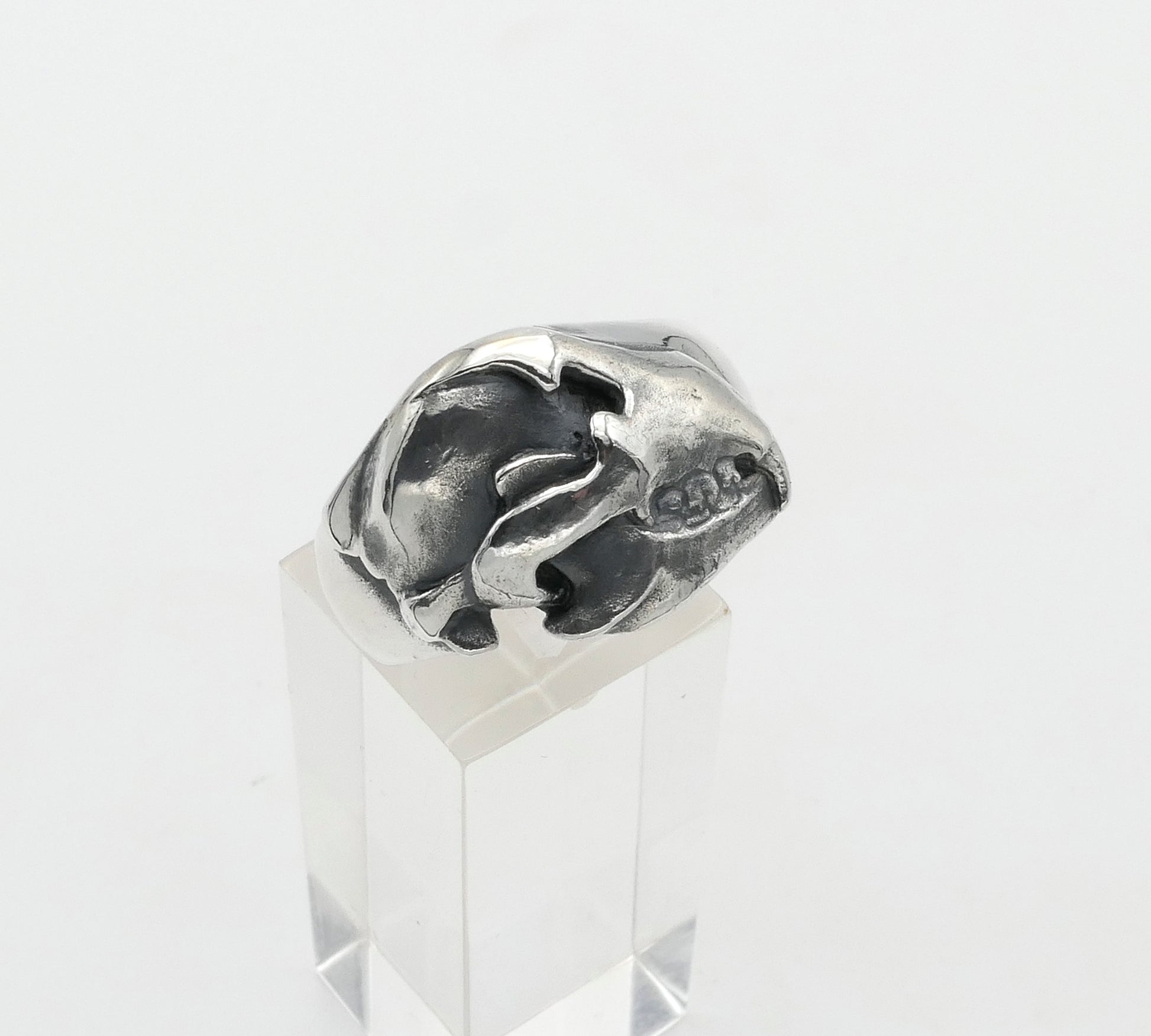 Silver bear skull ring on a clear stand against a white background
