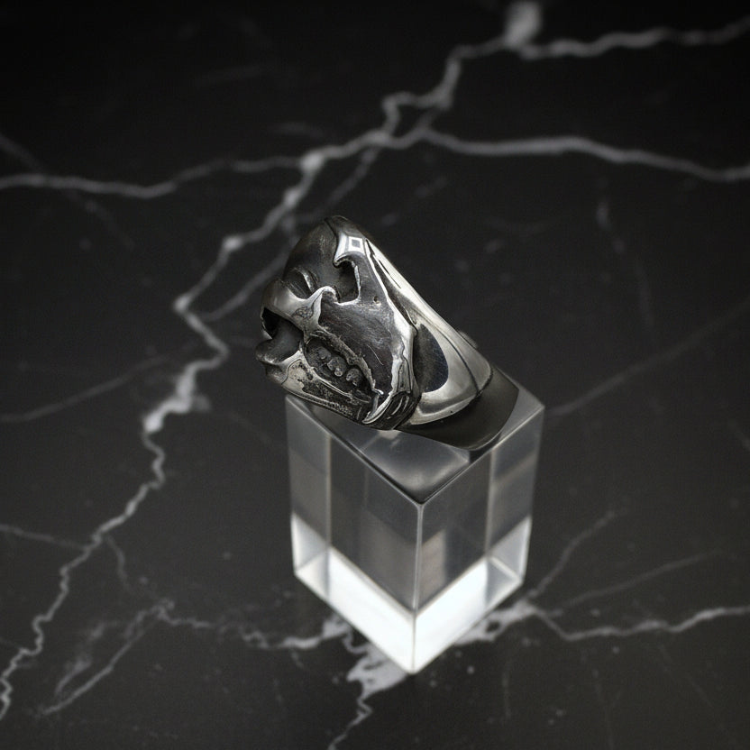 Silver ring on a clear stand against a dark marble background