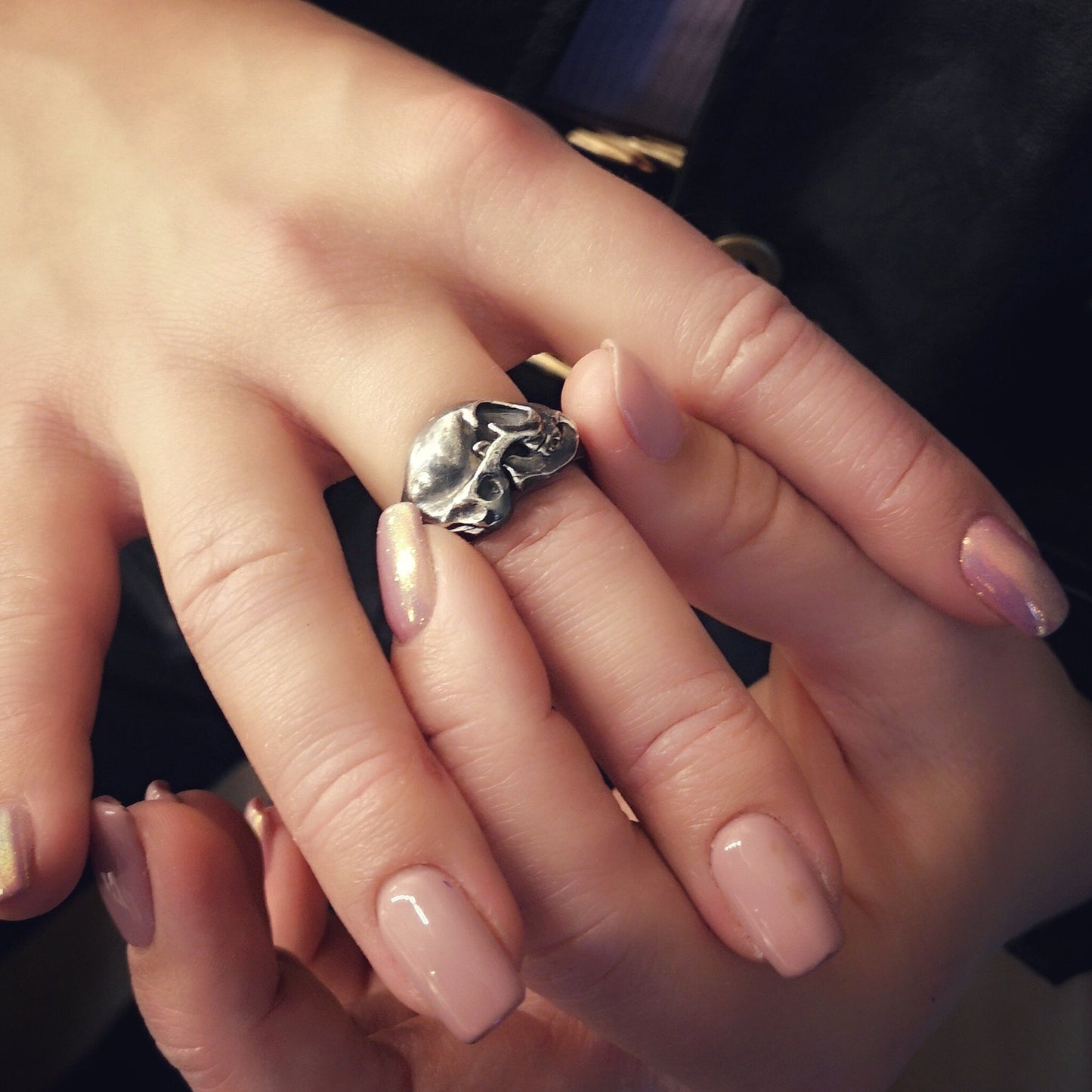Silver cat skull ring on a human finger