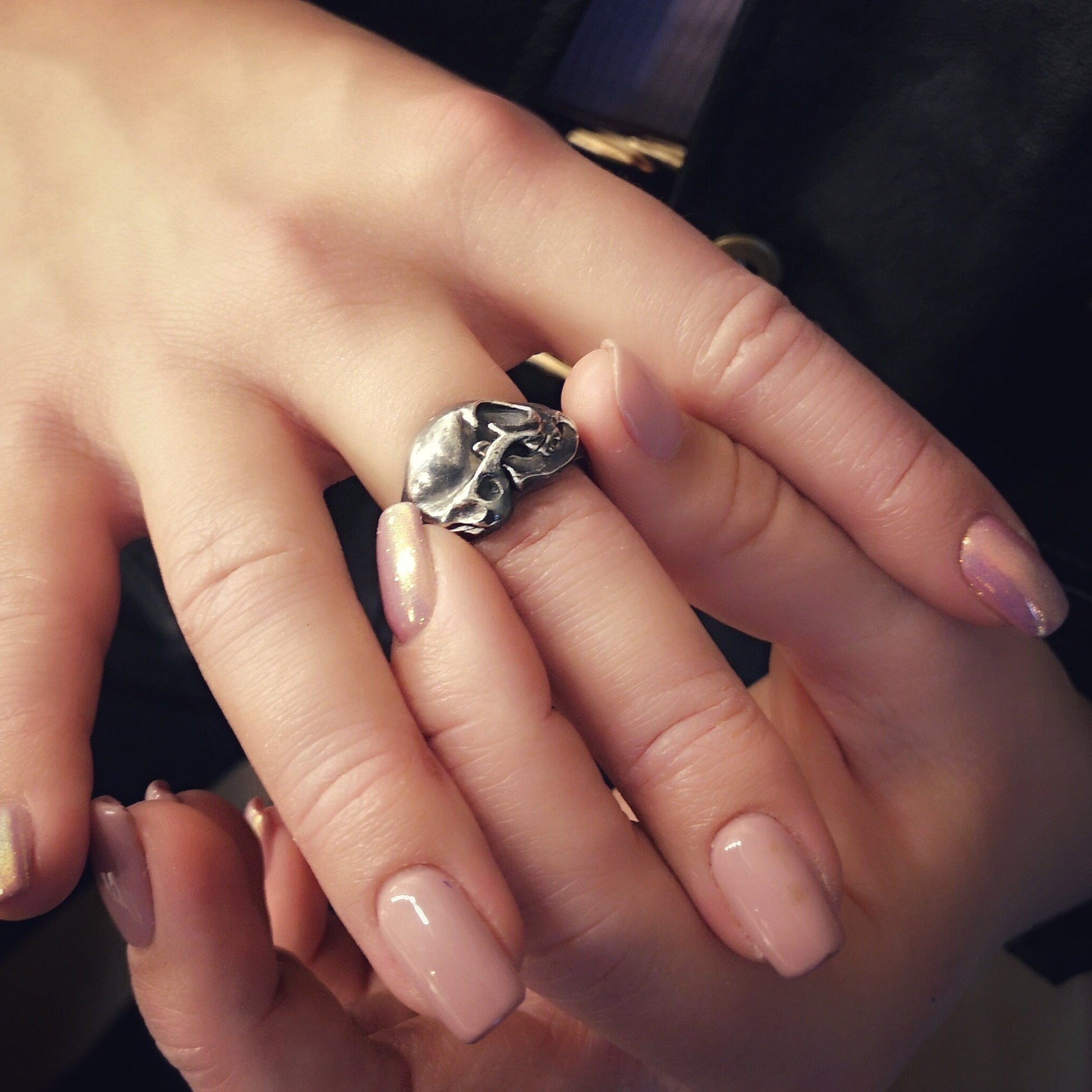 Silver cat skull ring on a human finger
