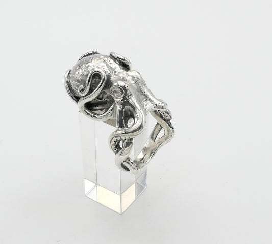 Silver octopus ring with intricate design on a clear stand against a white background