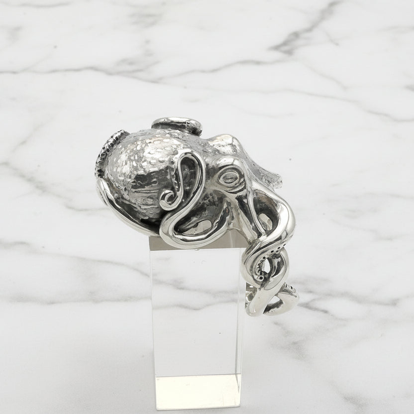 Silver octopus ring on a clear stand against a white background