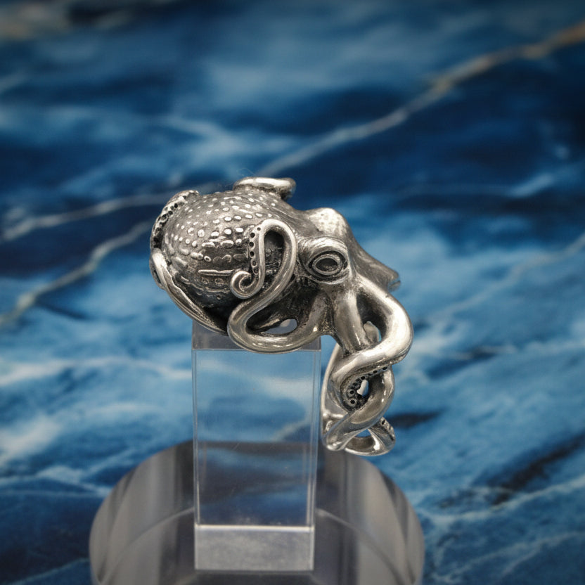 Silver octopus ring on a clear stand with a blue water background
