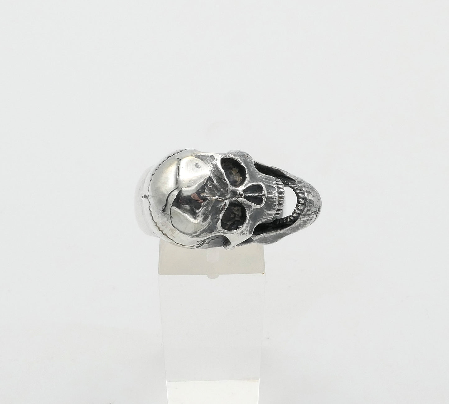 Silver skull-shaped ring on a white background