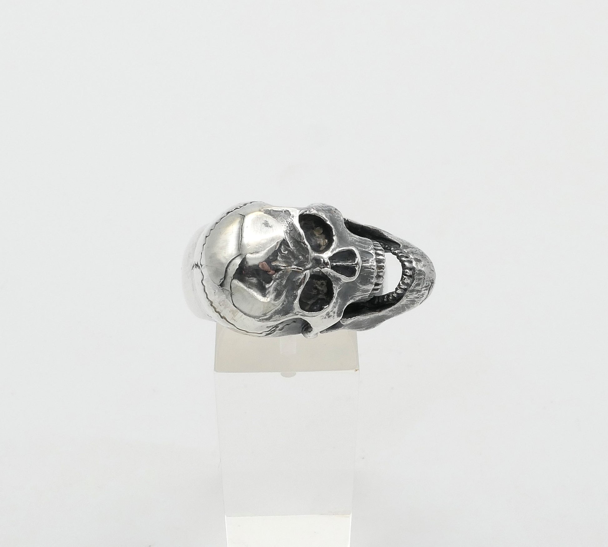 Silver skull-shaped ring on a white background