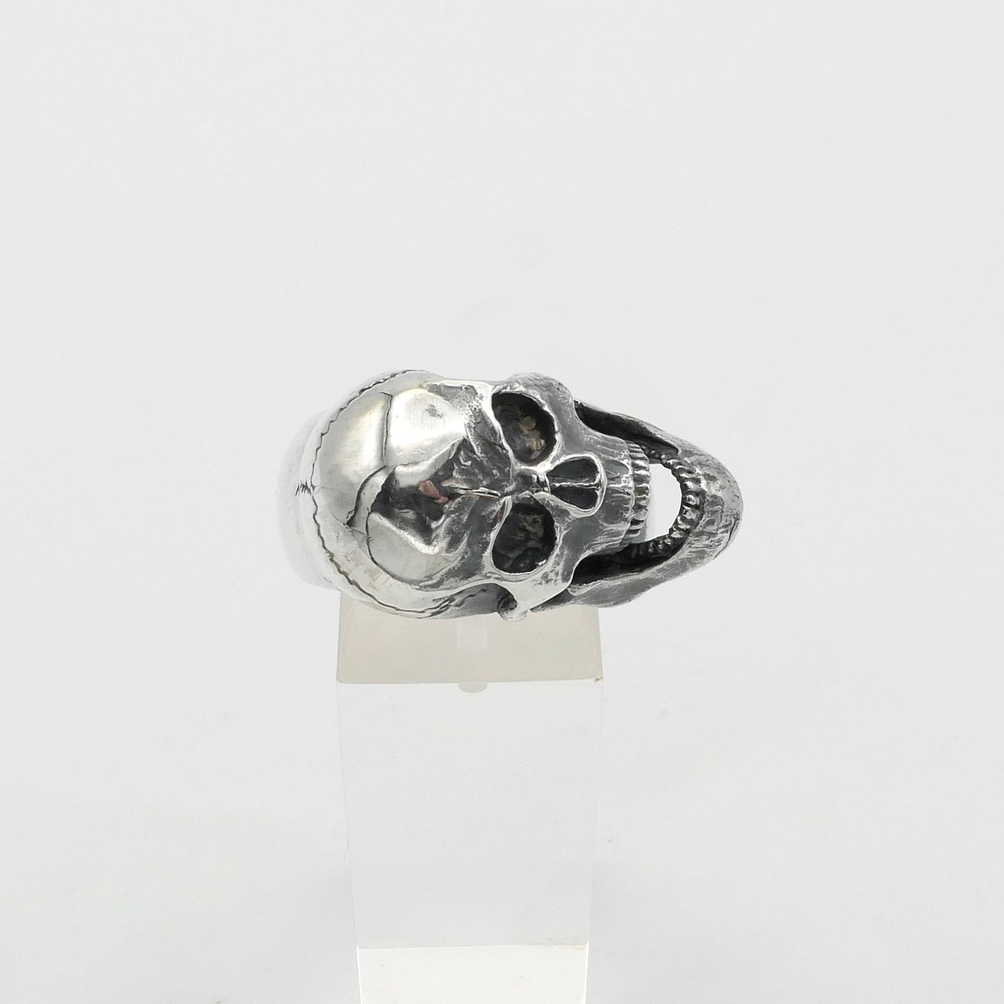 Silver skull-shaped ring on a white background