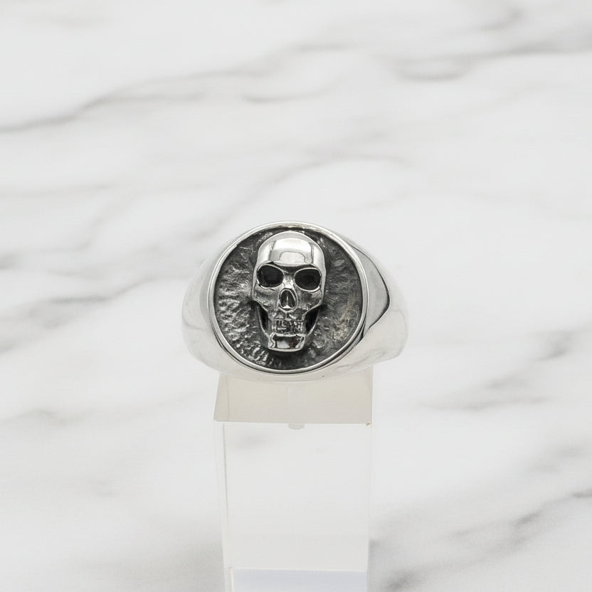 Silver skull signet ring on a white background