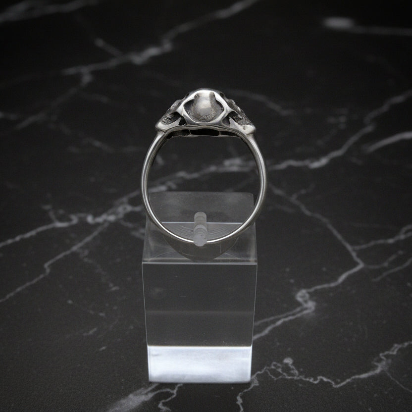Silver ring on a clear stand against a dark marble background