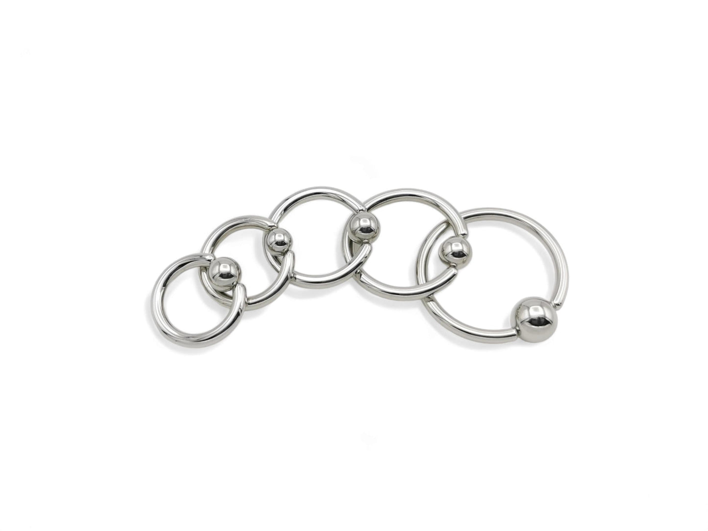 A collection of surgical steel ball closure rings in various sizes, with a polished metallic finish.