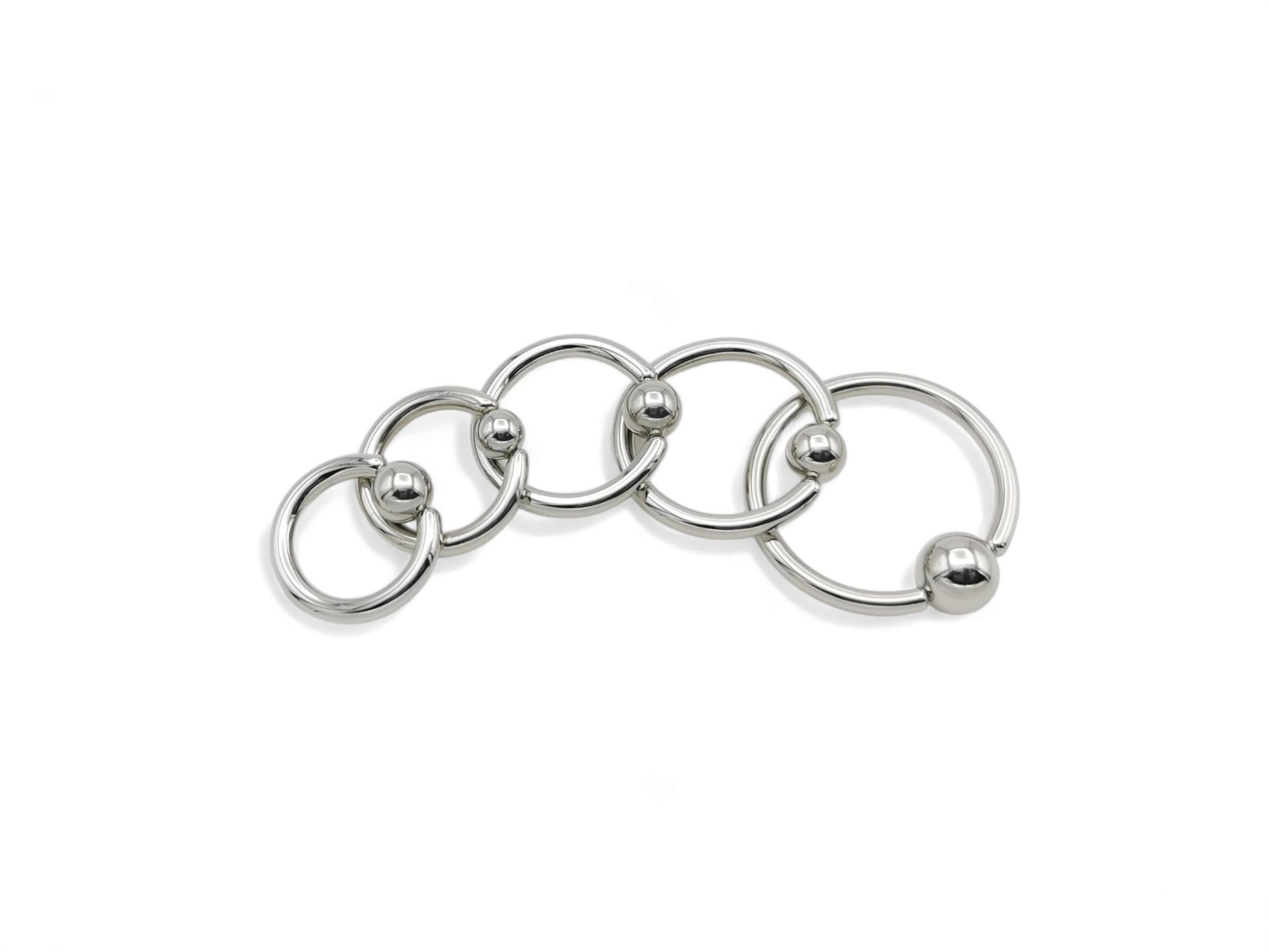 A collection of surgical steel ball closure rings in various sizes, with a polished metallic finish.