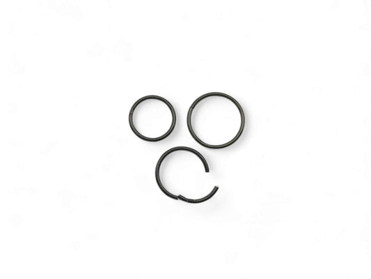 Three black surgical steel clicker rings for nose piercings, placed against a white background.