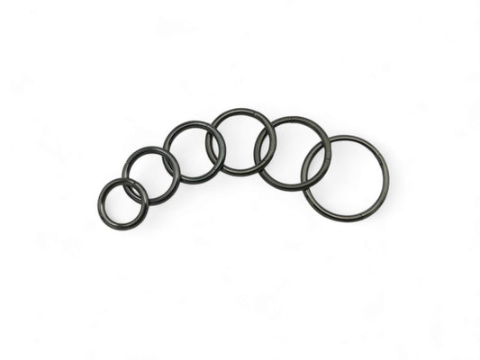 A set of six black surgical steel clicker rings arranged in parallel against a white background.