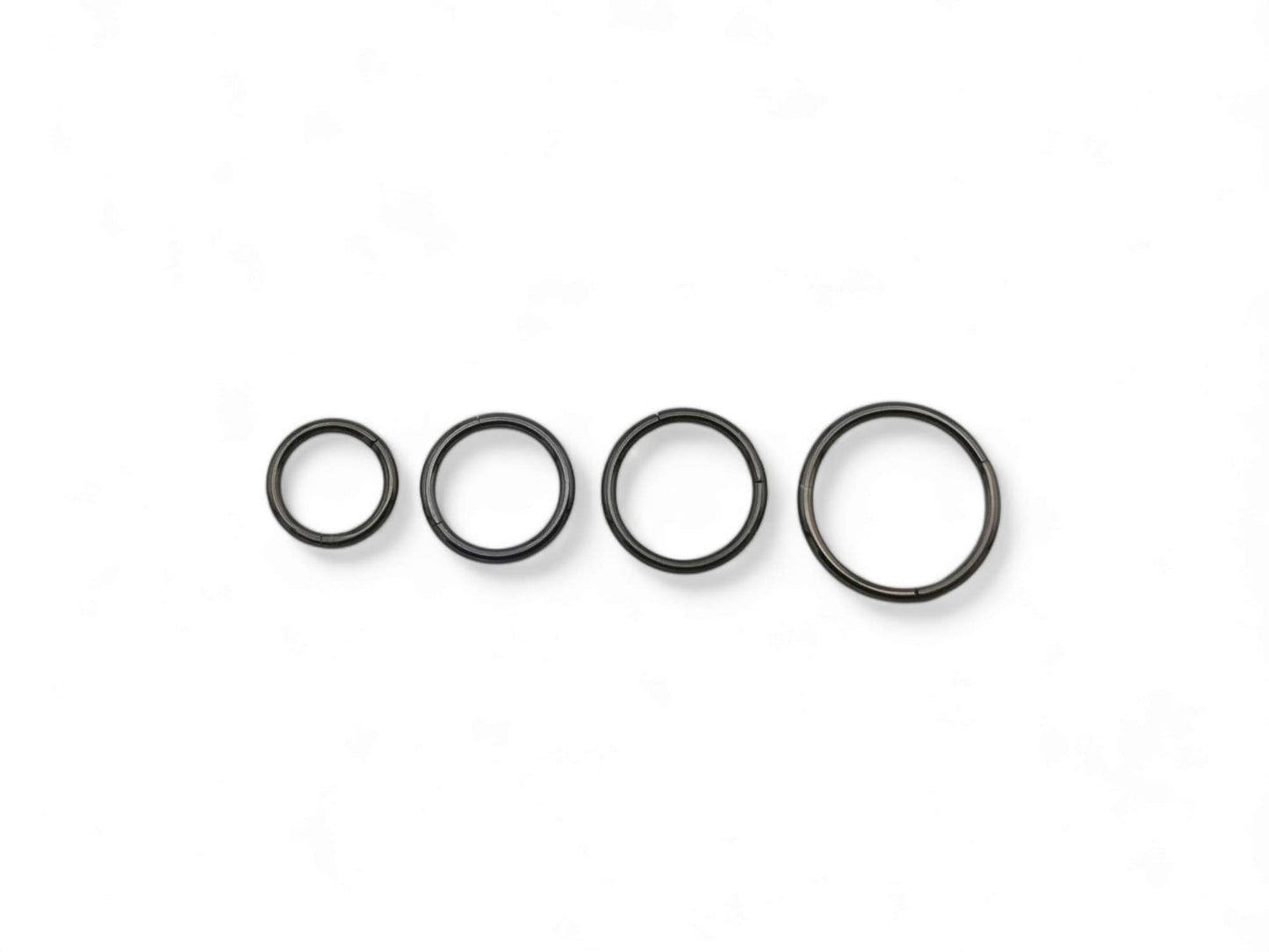 Three black surgical steel clicker rings for ear and nose piercings, presented on a white background.