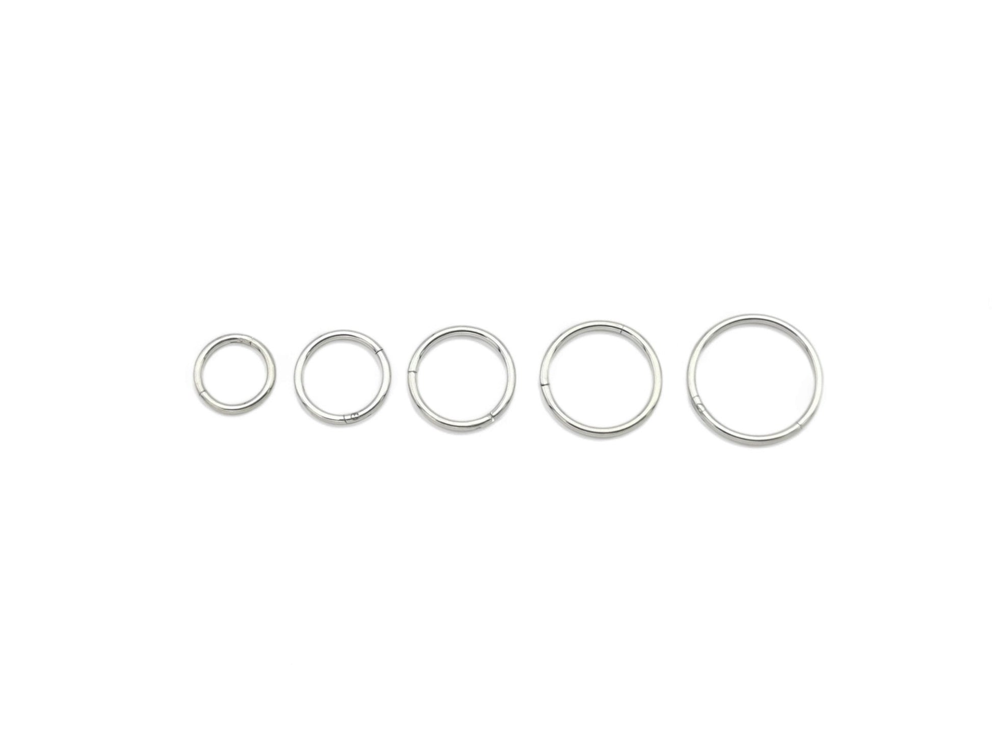 A set of five silver surgical steel clicker rings, with varying internal diameters for ear and nose piercings.