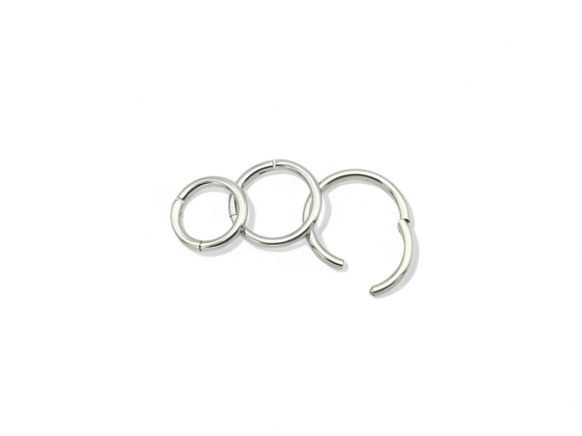 A set of three surgical steel clicker rings in increasing sizes, arranged in a triangular formation, with a shiny metallic finish.