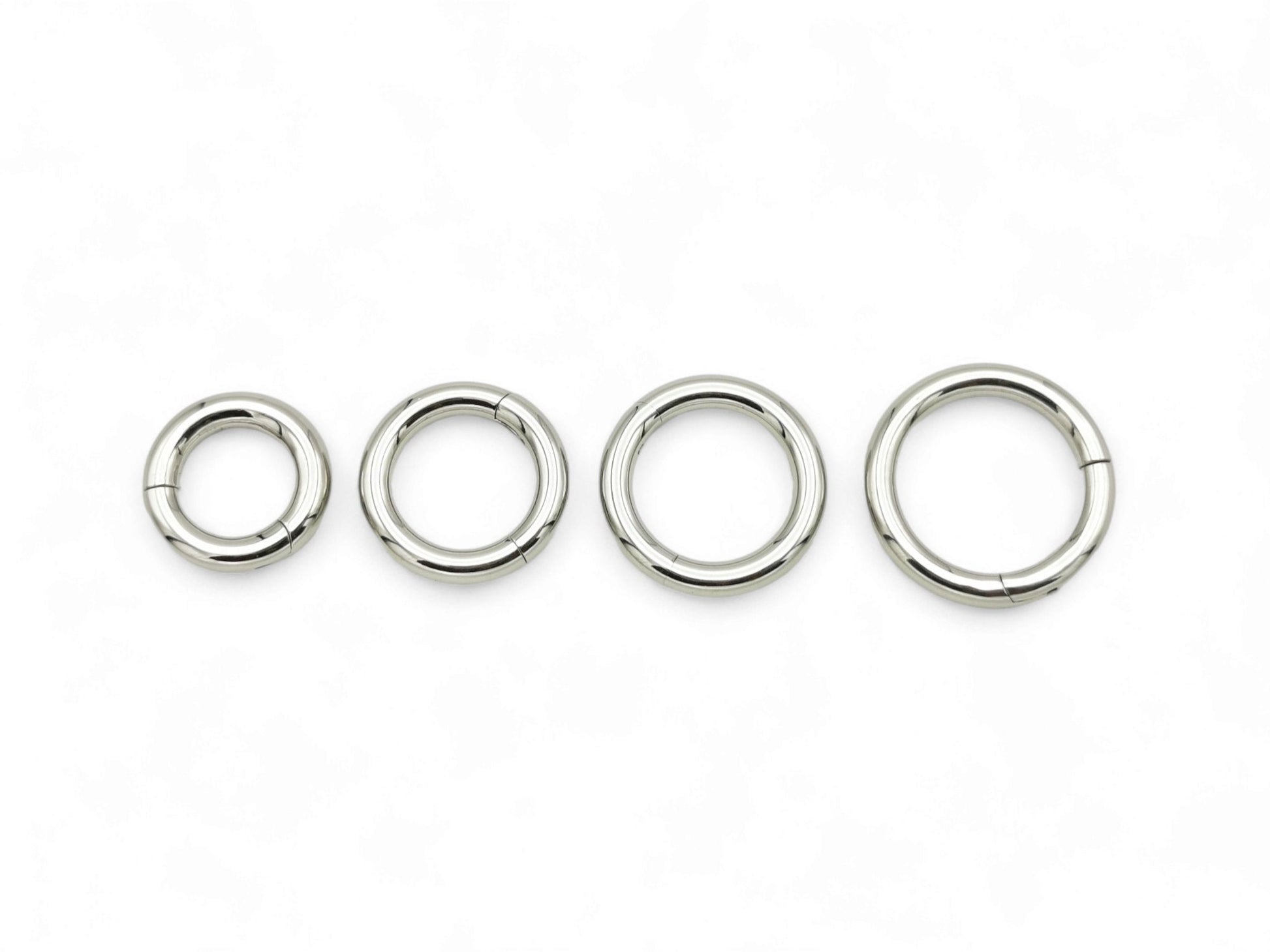 A set of four silver surgical steel clicker rings for body piercing, displayed on a white background.