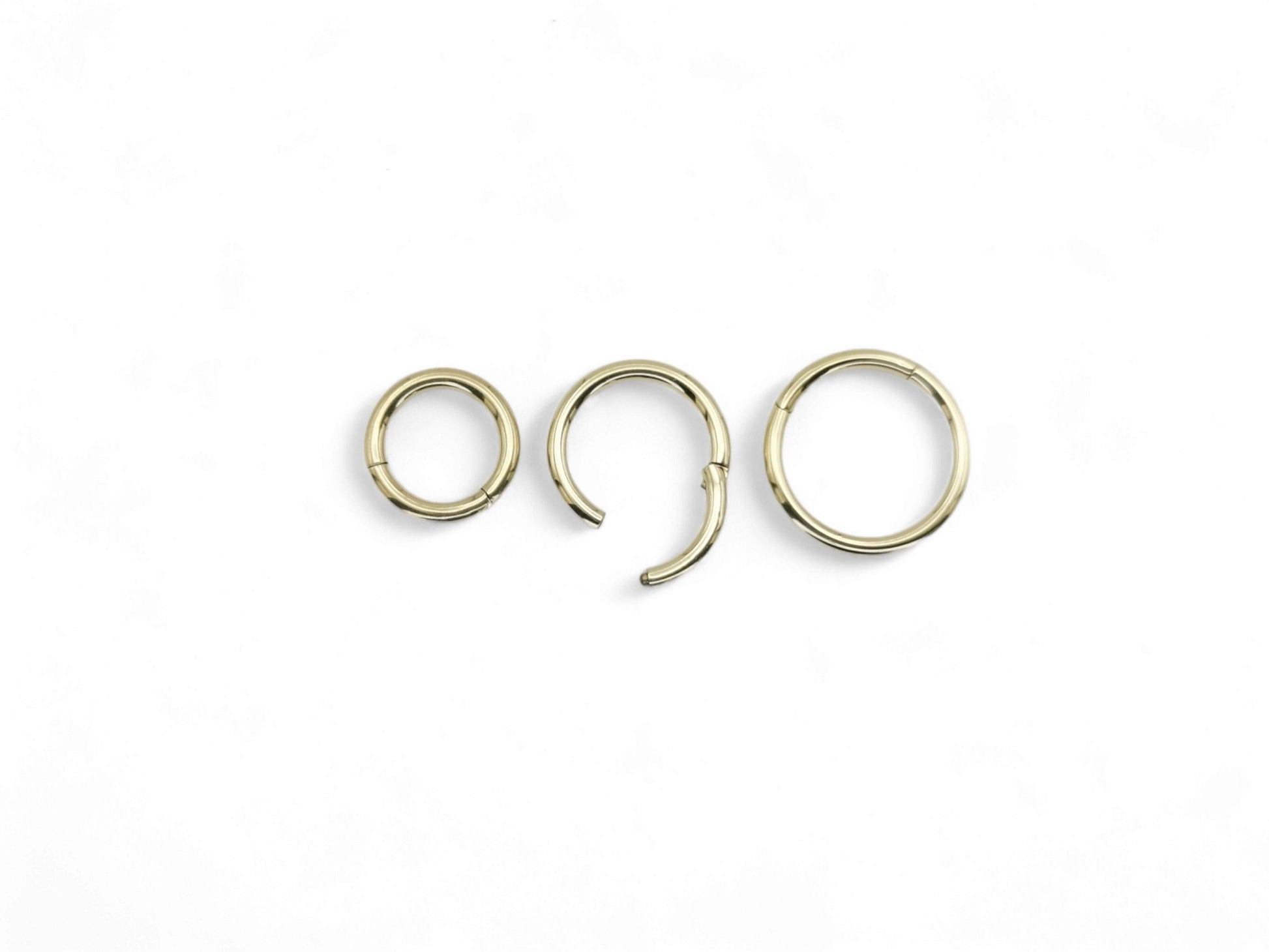 Three gold-colored surgical steel clicker rings for body piercings, displayed on a white background.
