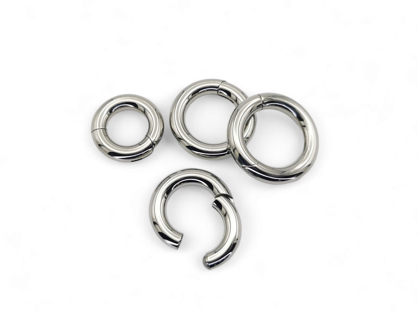 A set of four silver-colored titanium clicker rings for piercings, displayed on a white background.