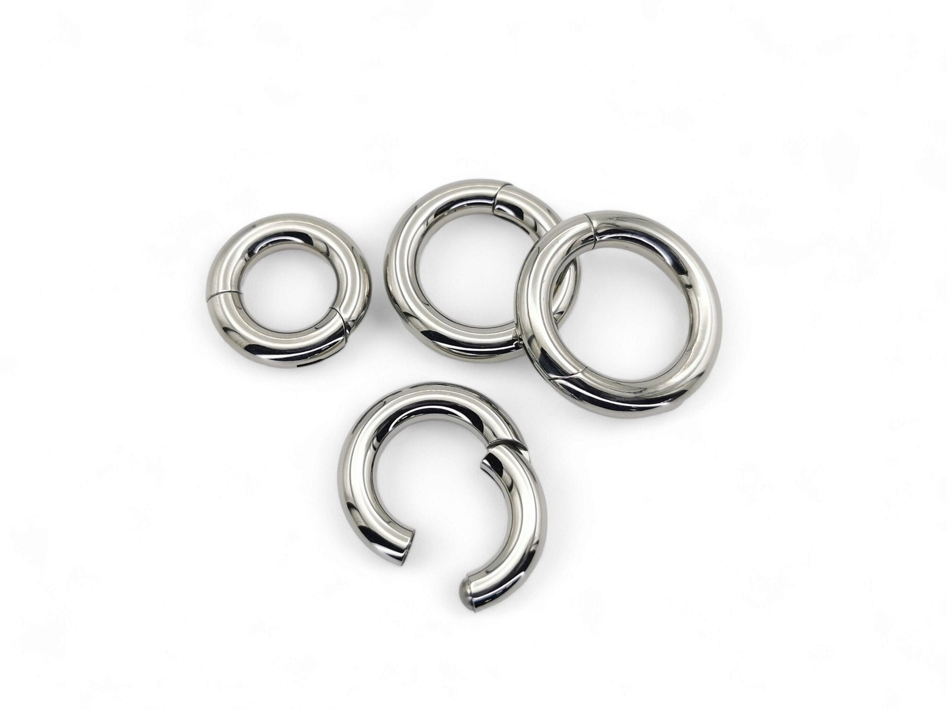 A set of four silver-colored titanium clicker rings for piercings, displayed on a white background.