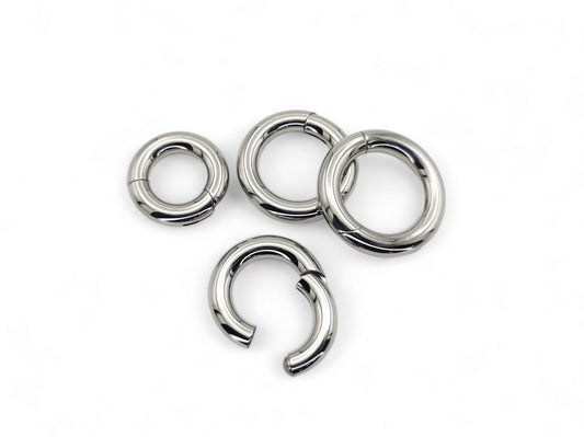 A set of four silver-colored titanium clicker rings for piercings, displayed on a white background.