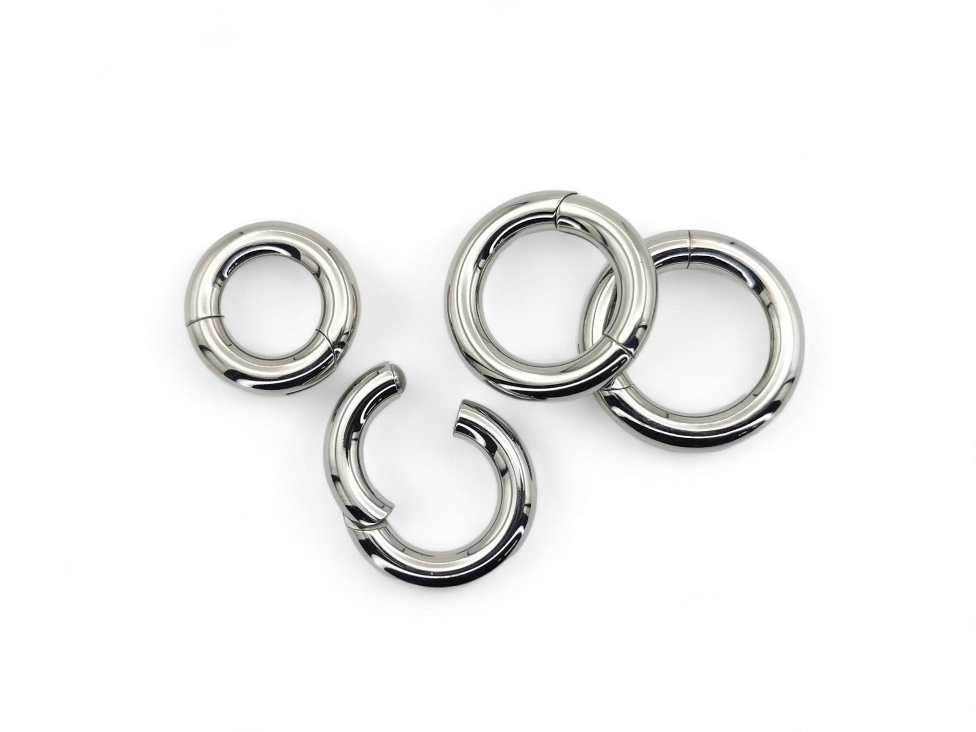 A set of four silver-colored titanium clicker rings for piercings, displayed on a white background.