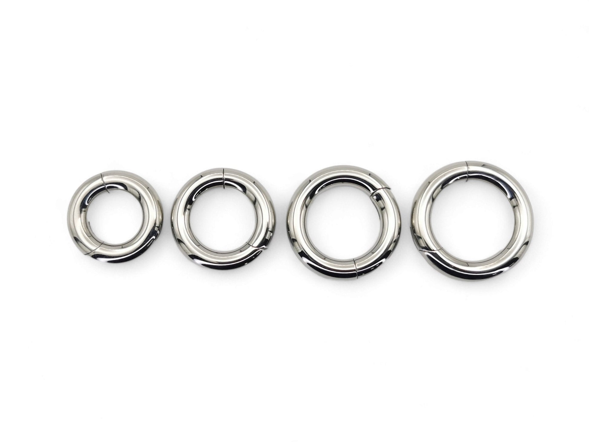 A set of four silver-colored titanium clicker rings for piercings, displayed on a white background.