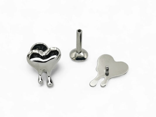 A silver-colored titanium melting heart stud jewelry piece displayed on a white background, consisting of a heart-shaped stud with a small ball on one end for piercing.