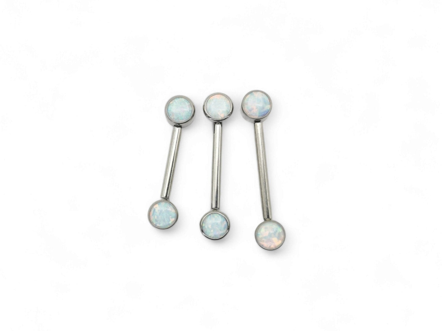 A set of three disc-shaped titanium nipple bars with bezel settings and white opal jewels.