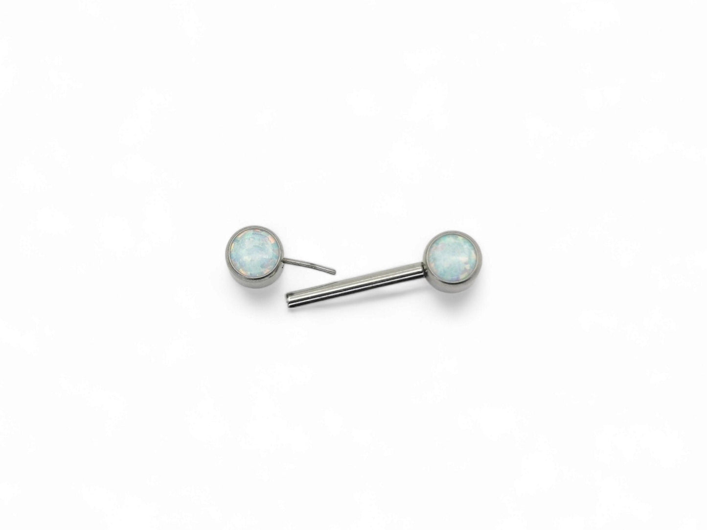 A disc-shaped titanium nipple bars with bezel settings and white opal jewels.