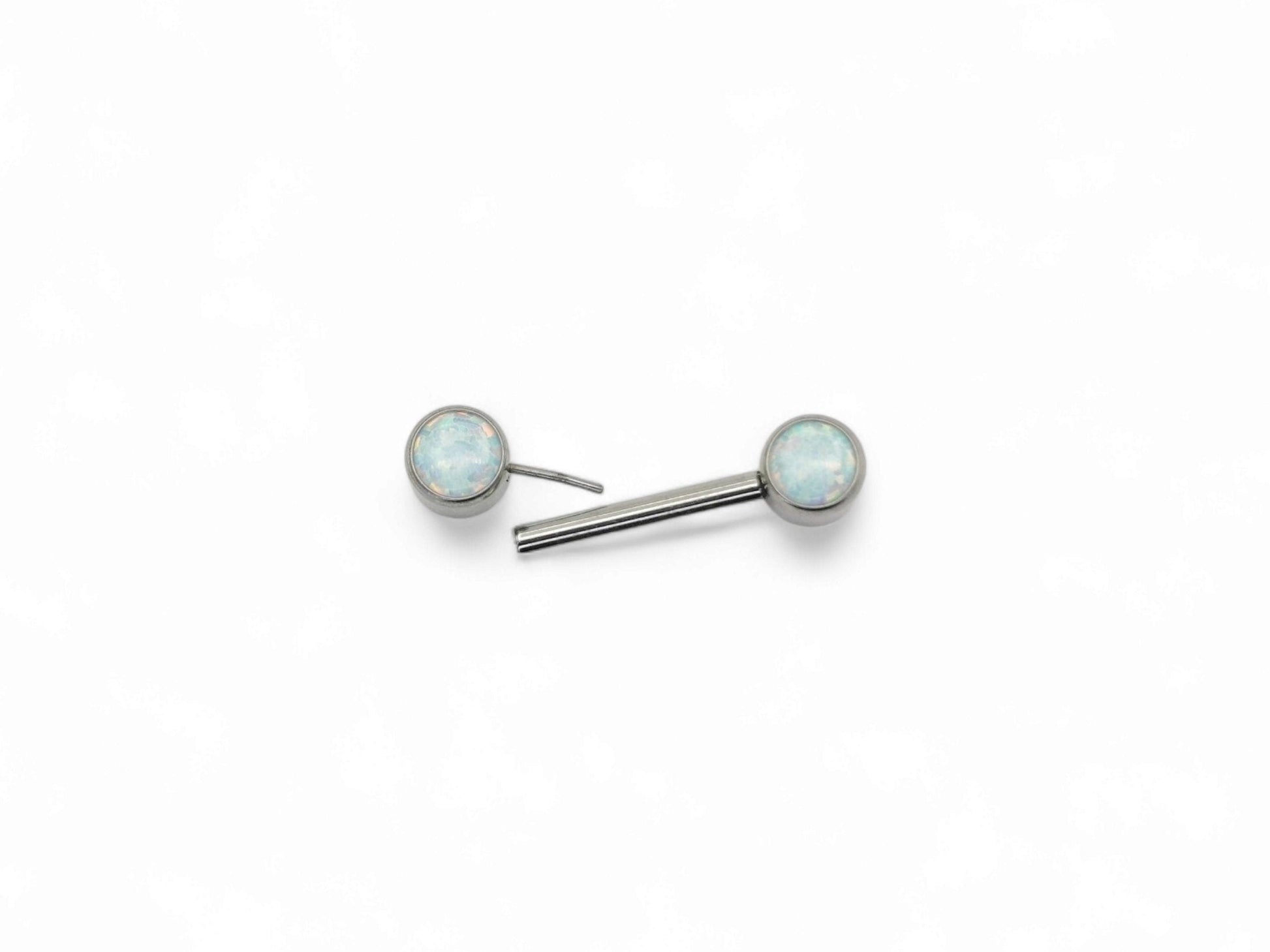A disc-shaped titanium nipple bars with bezel settings and white opal jewels.