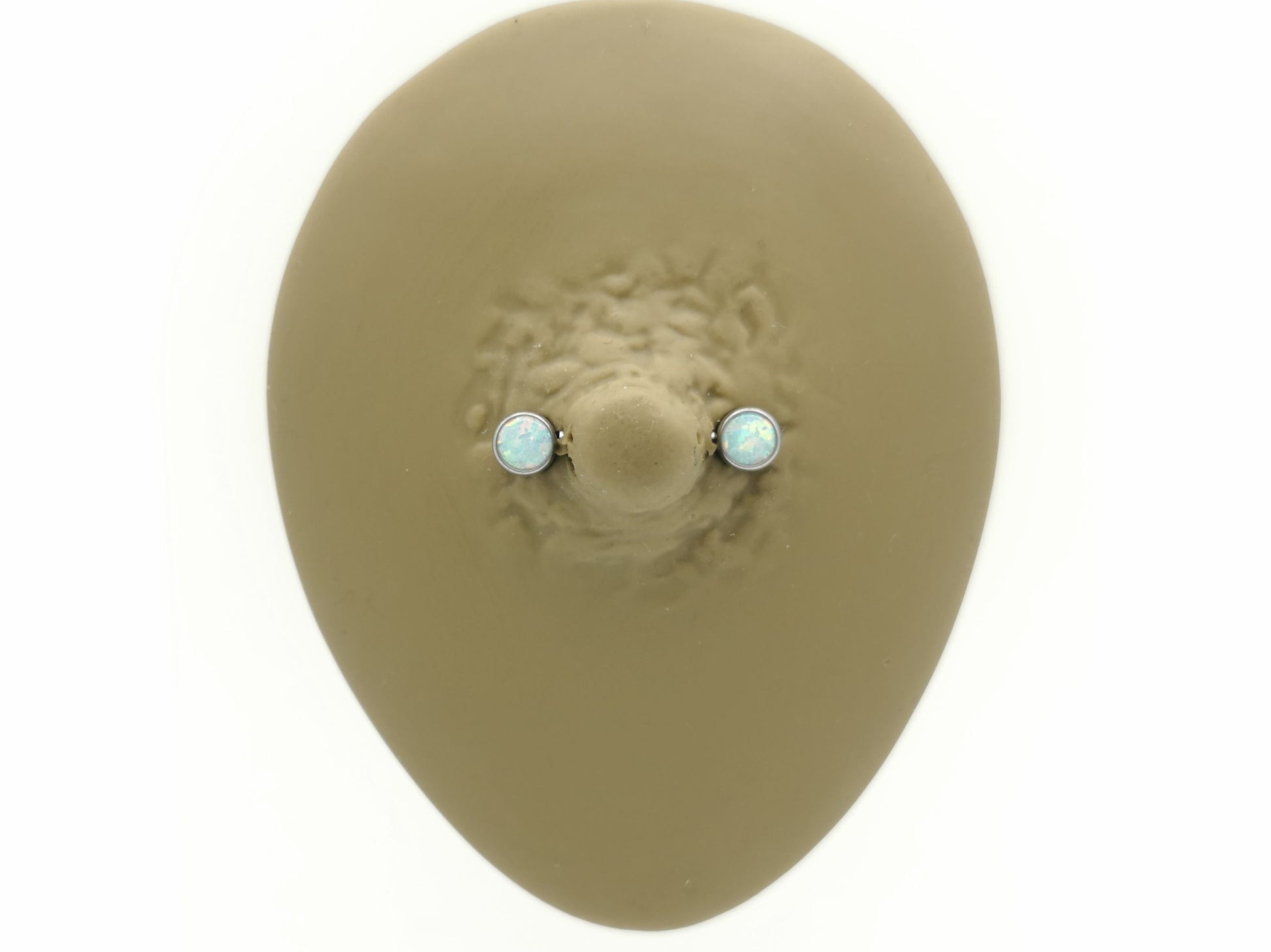 A disc-shaped titanium nipple bars with bezel settings and white opal jewels.