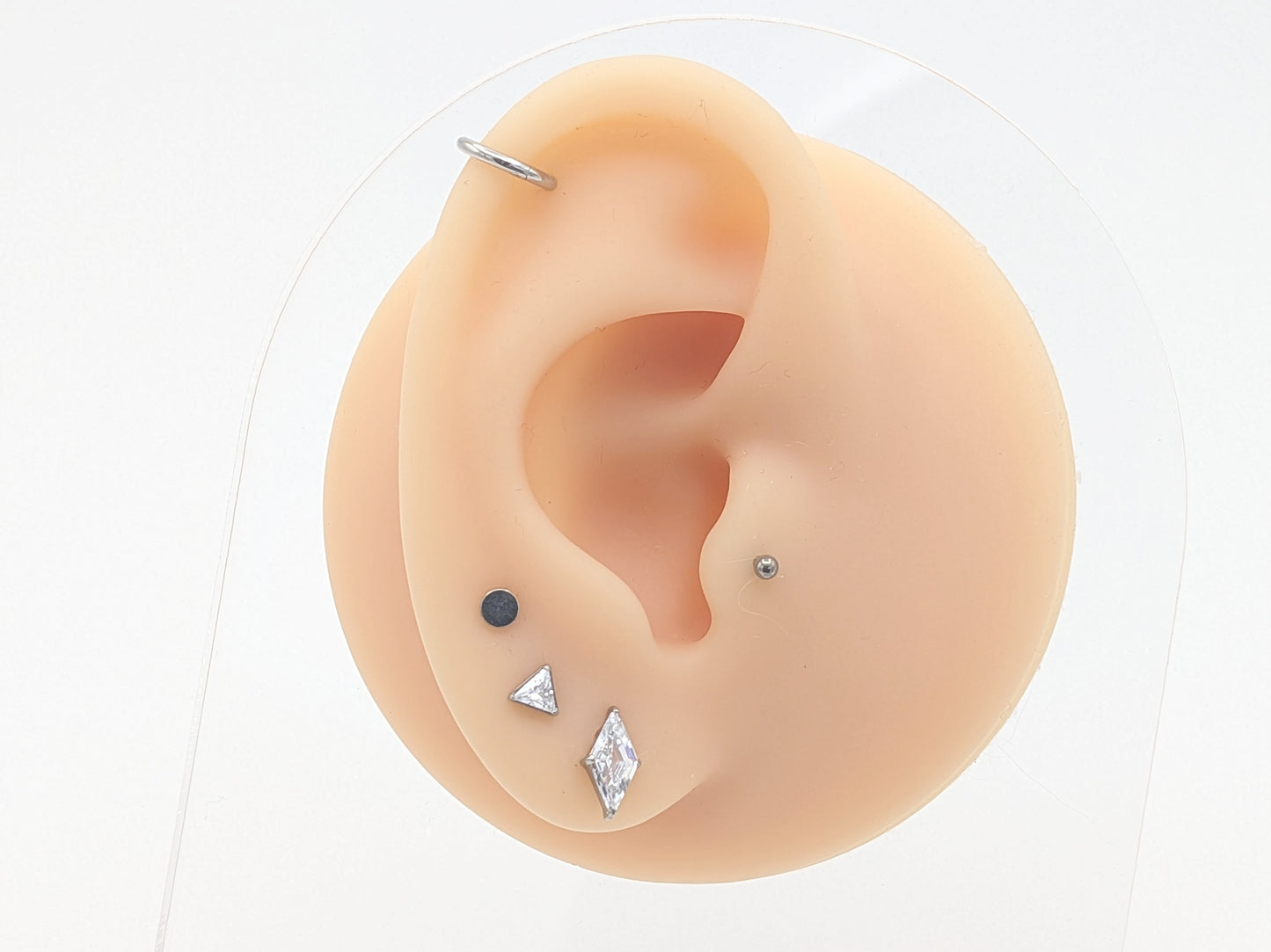 Ear with various earrings displayed on a white background