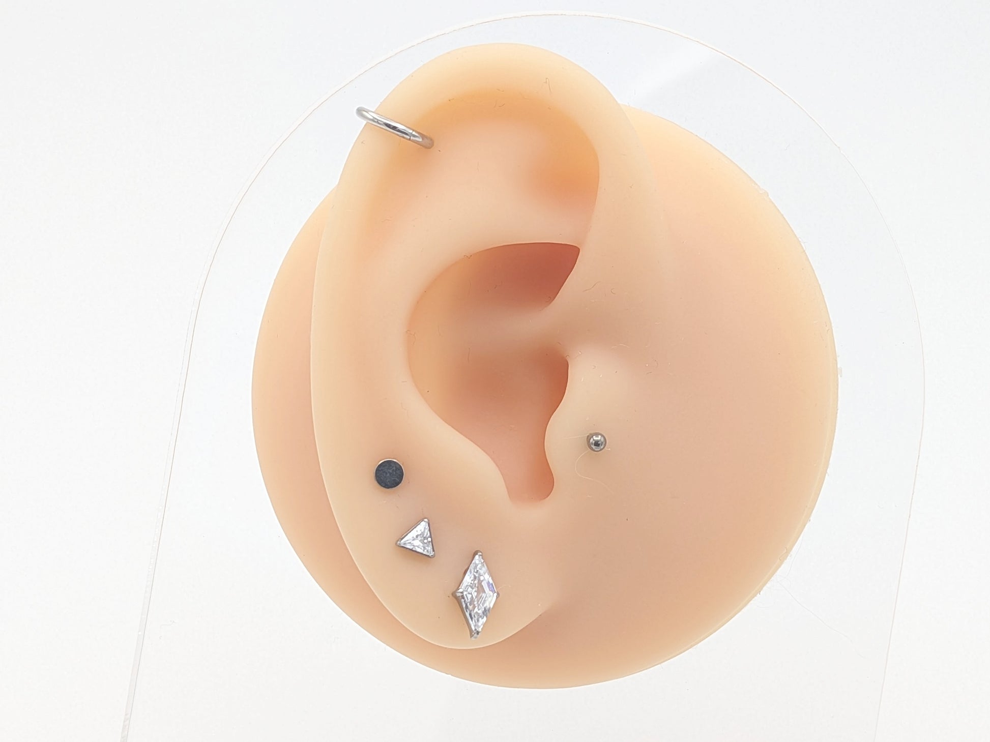 Ear with various earrings displayed on a white background