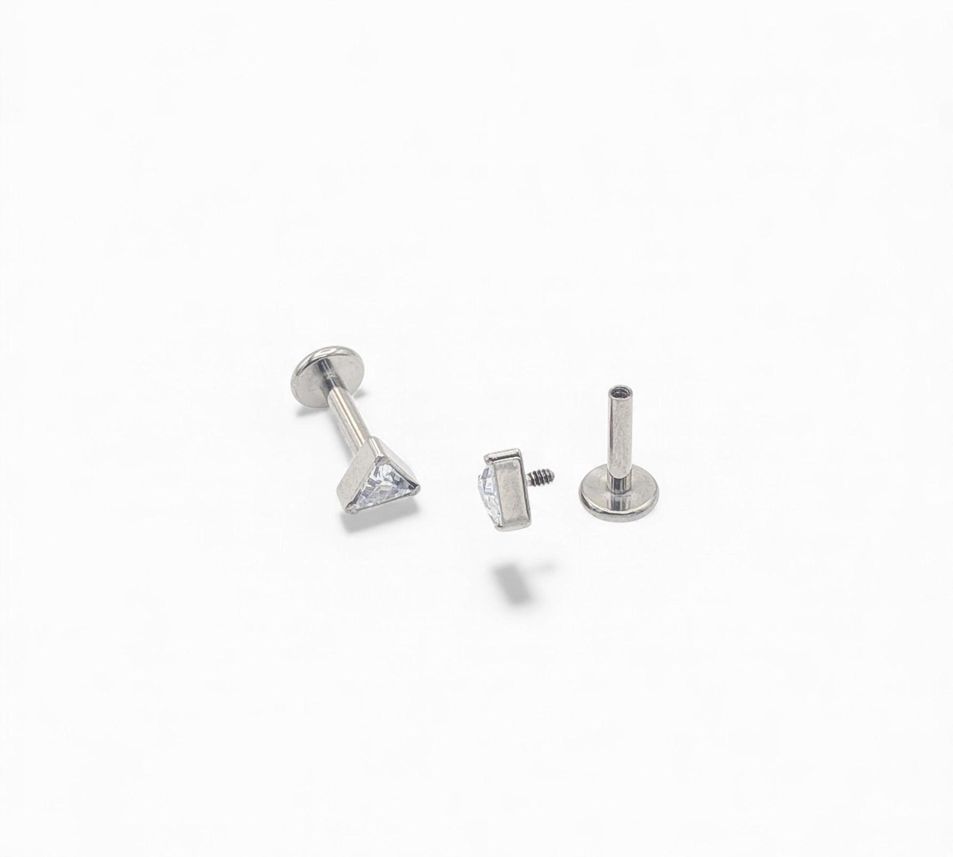 Three silver earring studs on a white background