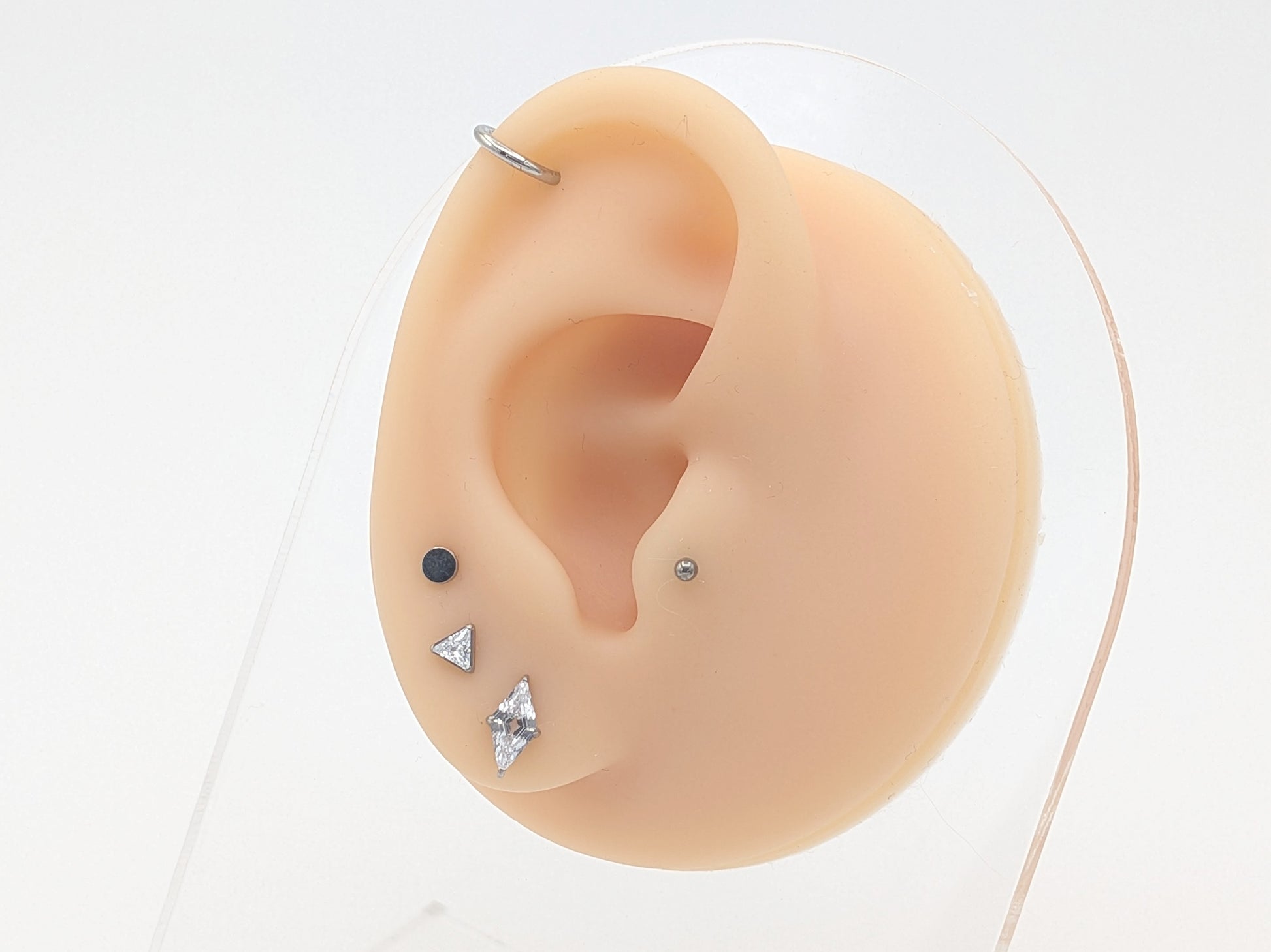 Close-up of a ear with three different styles of earrings on a white background