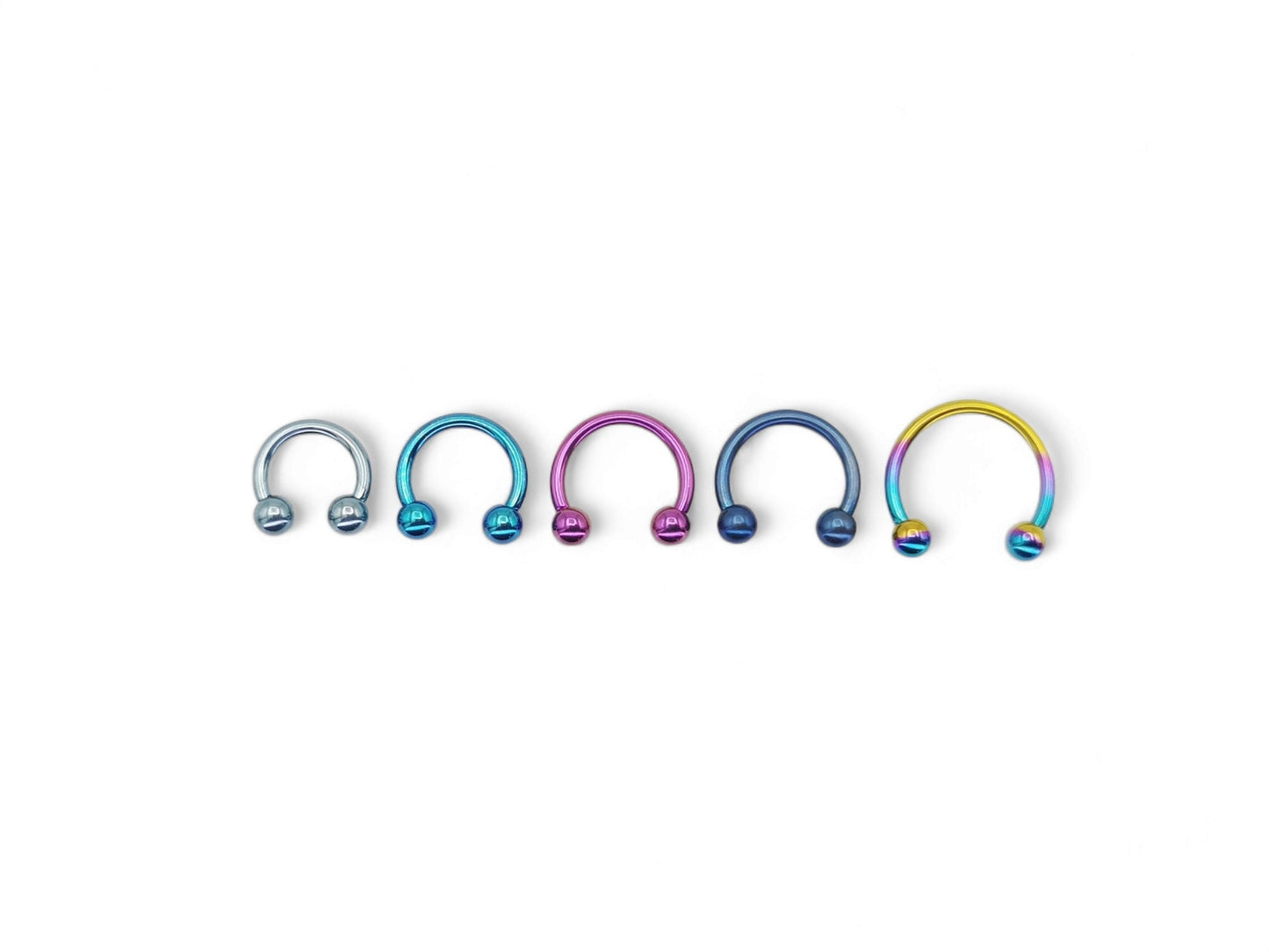 A selection of circular barbells in various colors, including blue, pink, and rainbow, designed for lip, ear, and septum piercings.