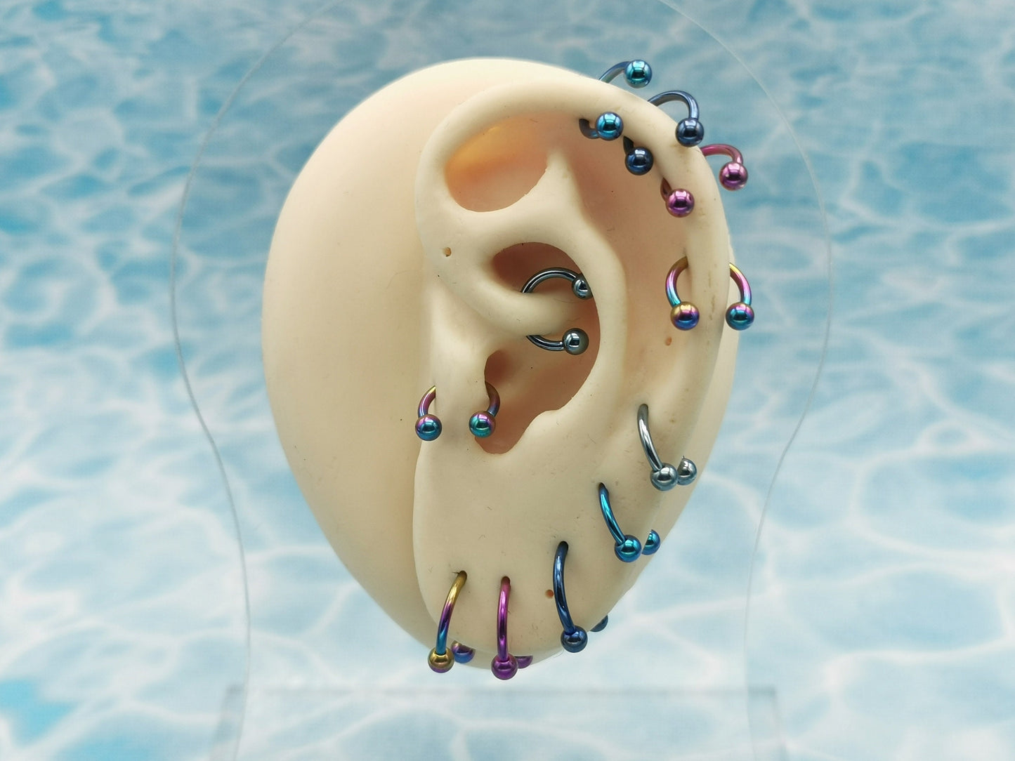 A selection of circular barbells in various colors, including blue, pink, and rainbow, designed for lip, ear, and septum piercings.