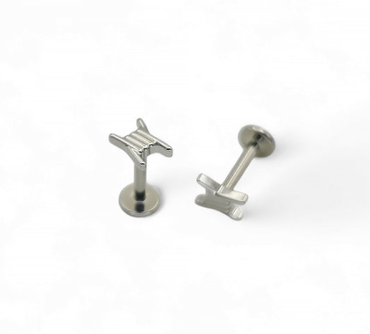 Two titanium barb wire threadless studs with a push-fit design, one standing upright and the other lying on its side on a white background.