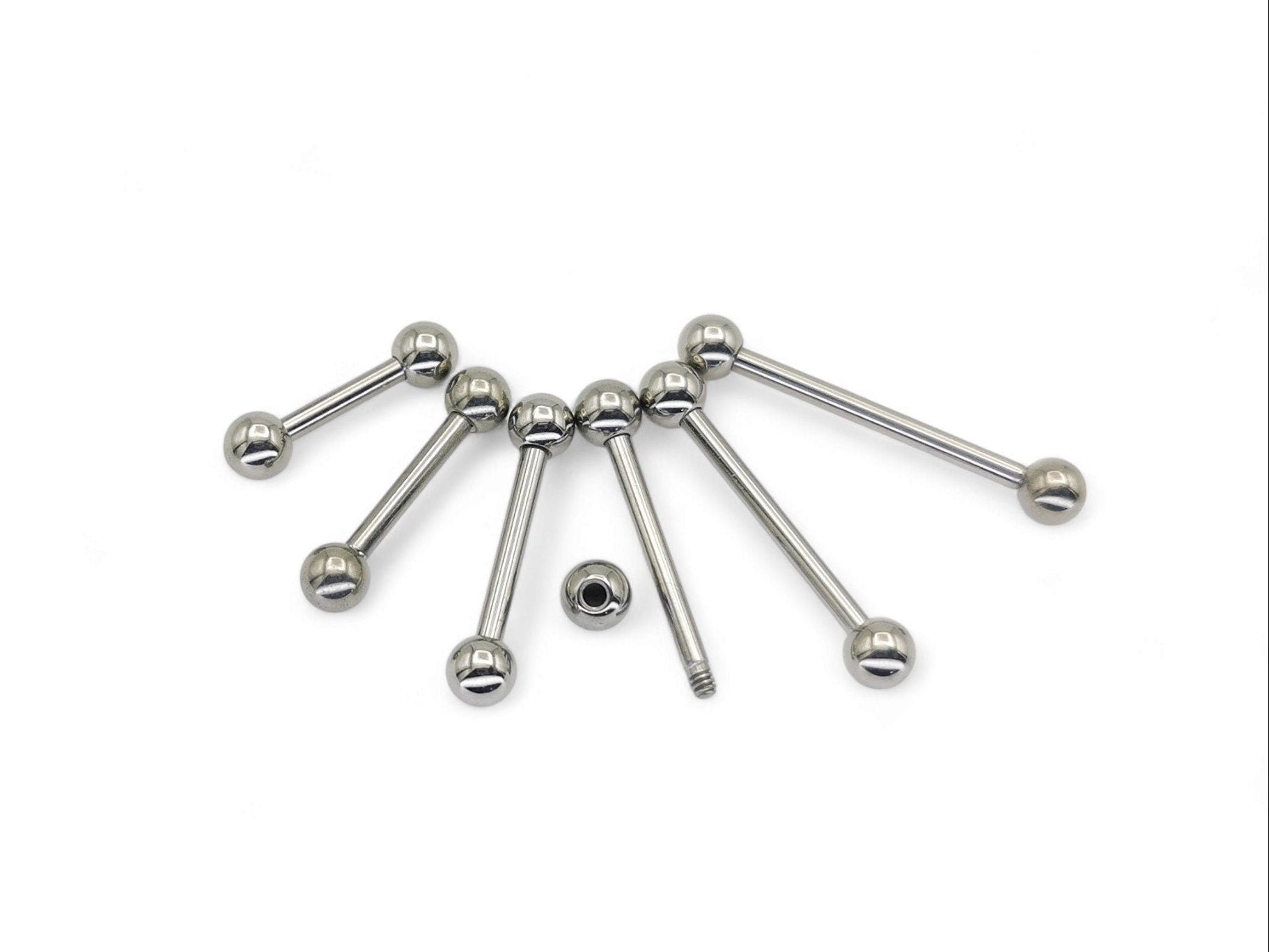 A set of polished titanium barbells with varying lengths, designed for piercings, presenting a metallic sheen.