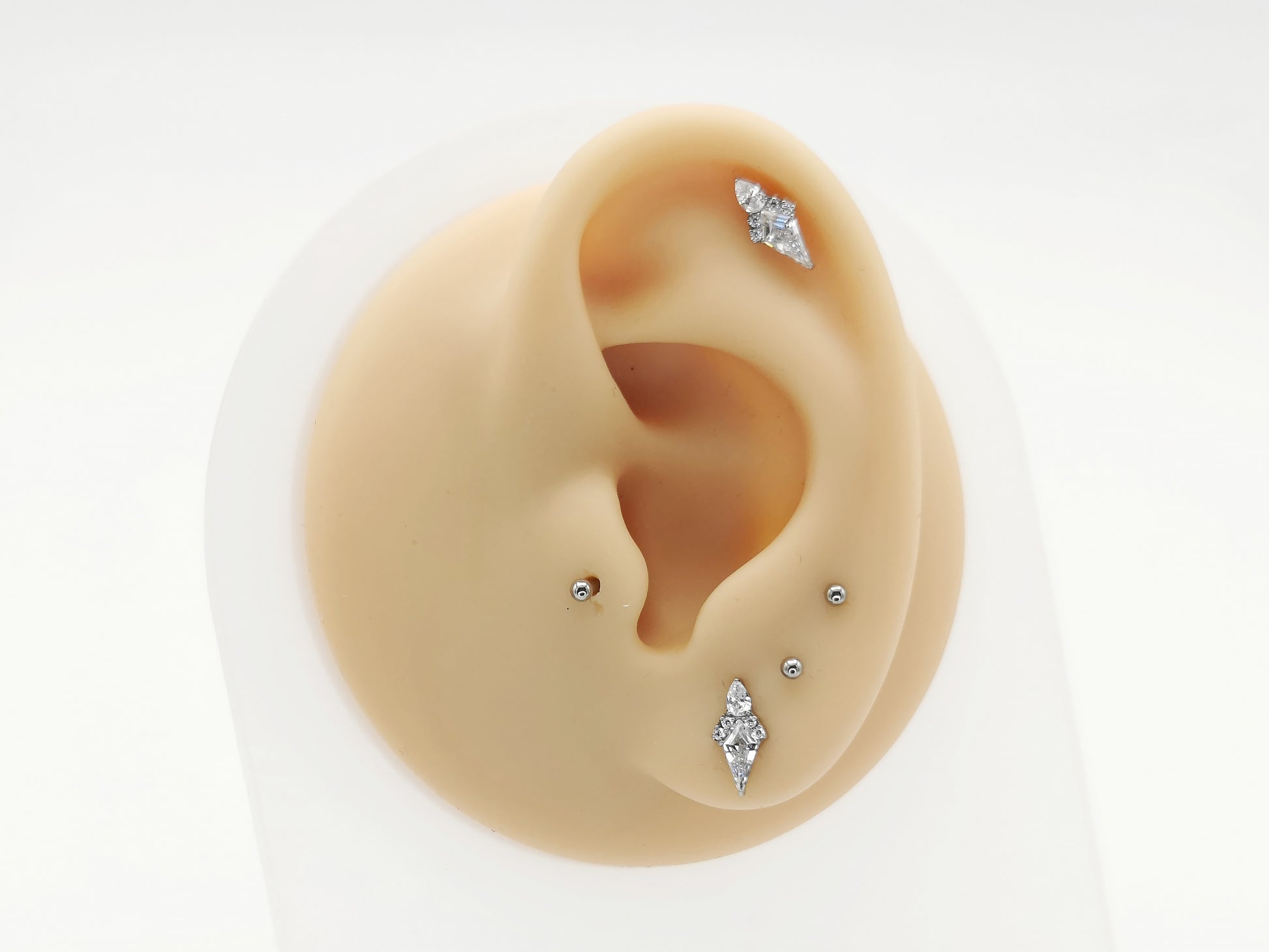 Titanium claw set kite studs on a mannequin ear
