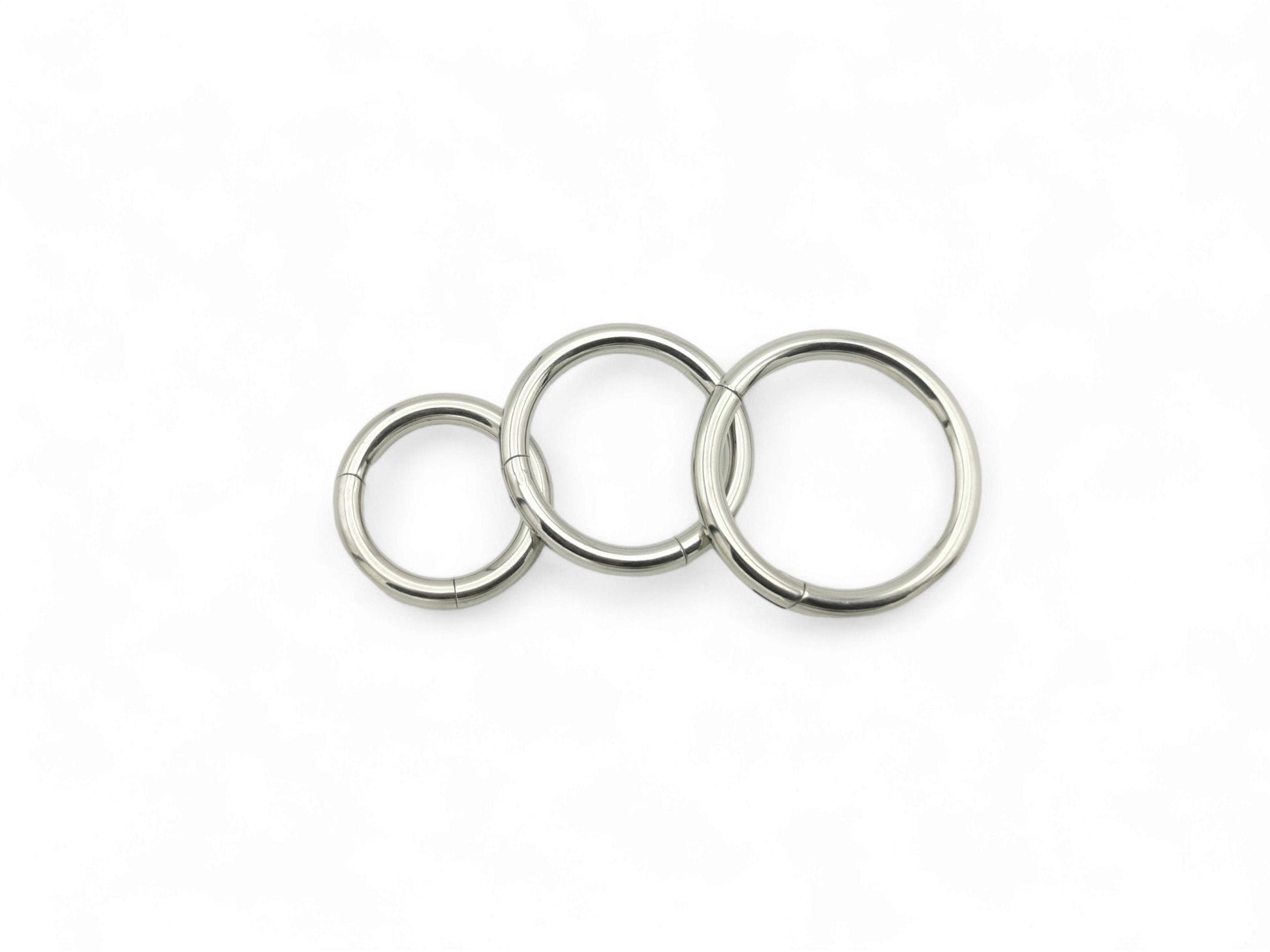 Three polished titanium clicker rings with a silver finish on a white background.