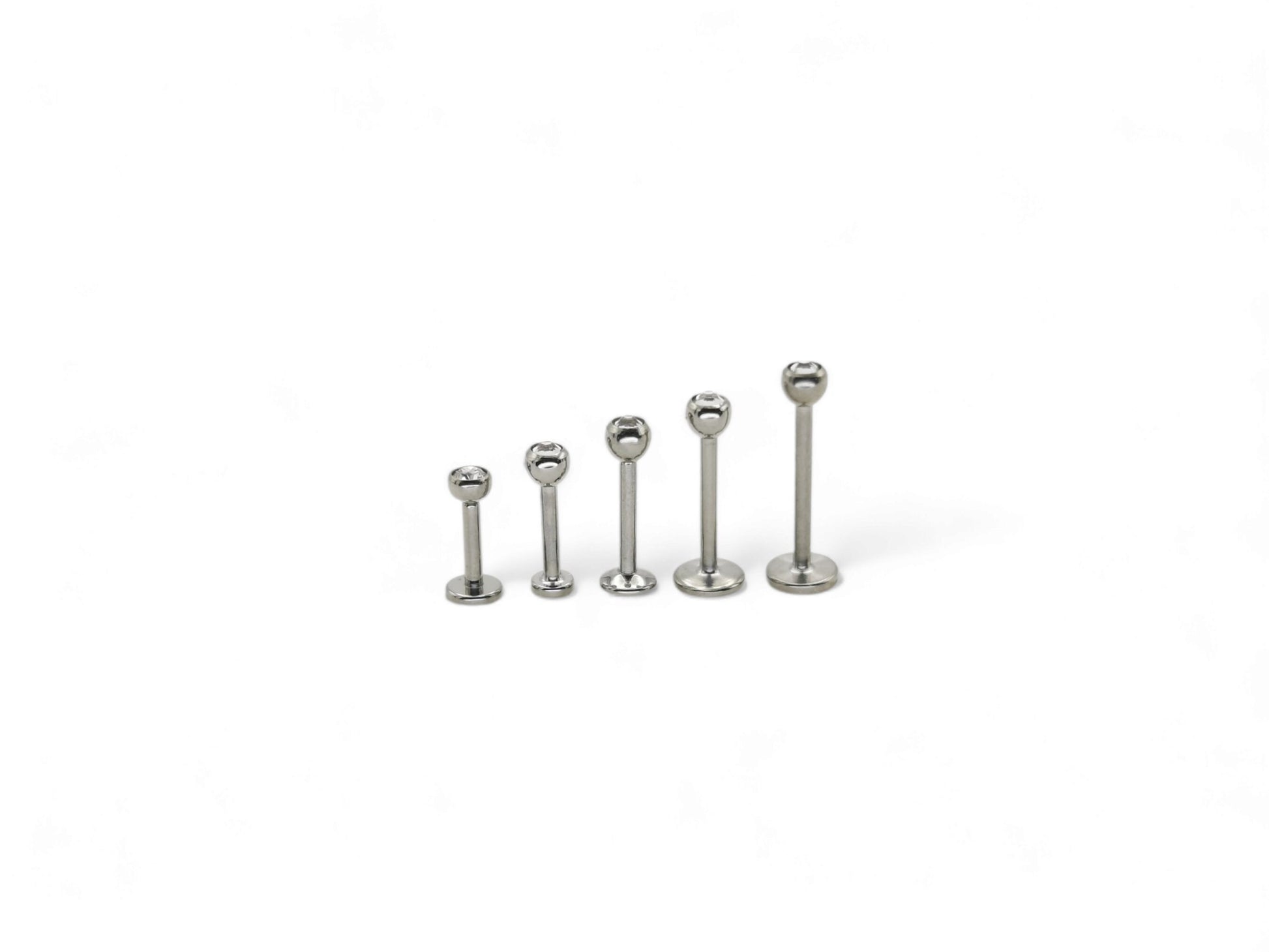 A collection of titanium threaded jewelled studs in various lengths, each featuring a clear crystal ball.