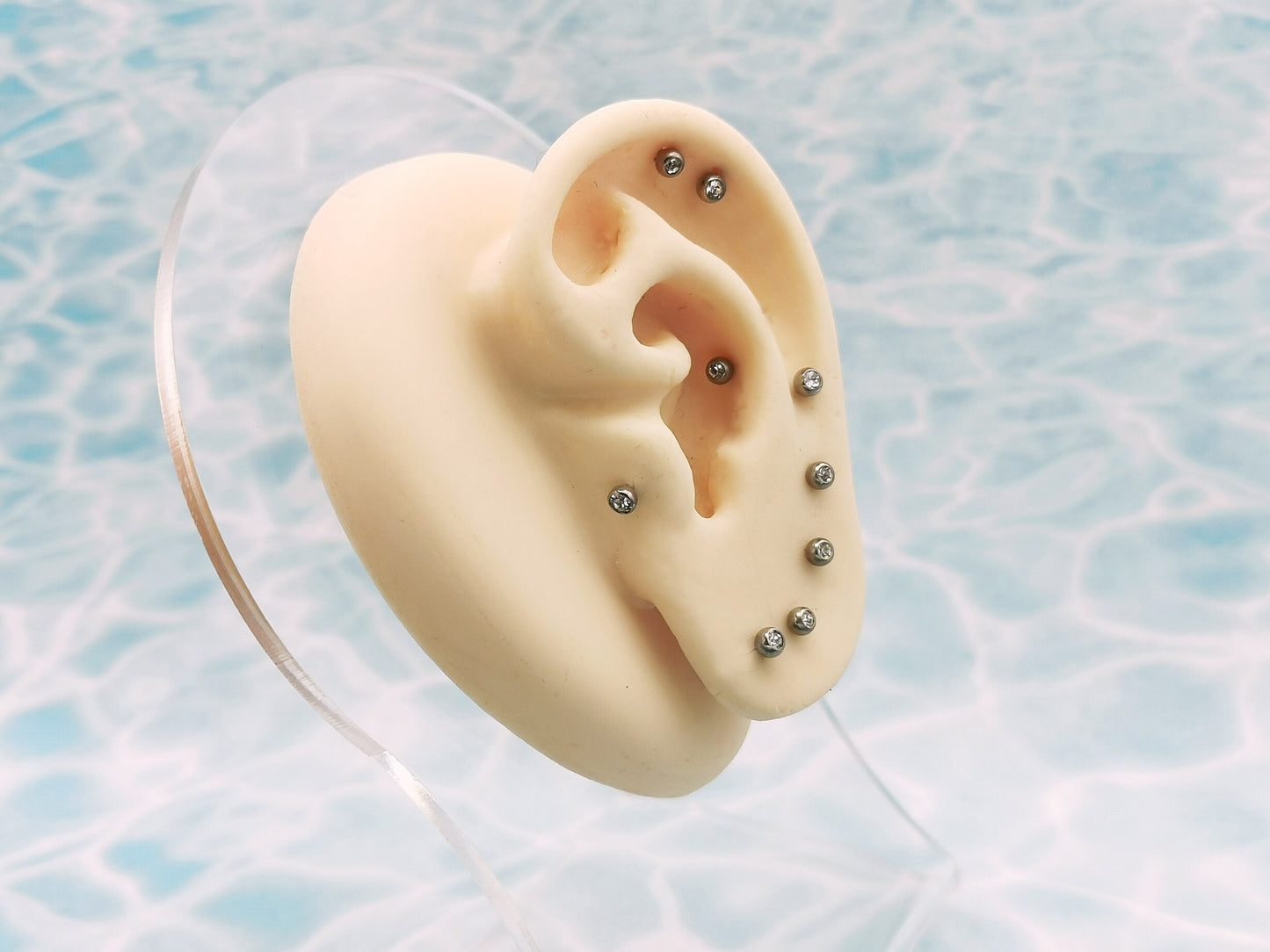 A collection of titanium threaded jewelled studs in various lengths, each featuring a clear crystal ball.